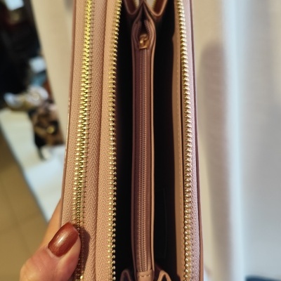 Carteira rosa com zíper dourado aberta mostrando interior