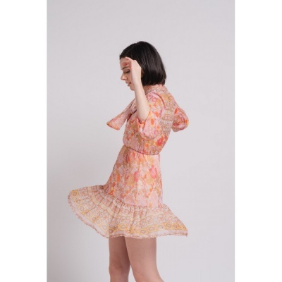 Vestido floral rosa e laranja com folho usado por mulher com cabelo curto