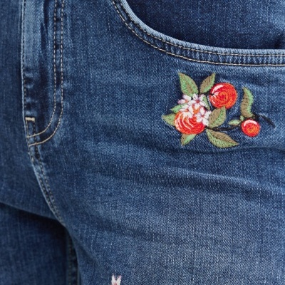 Calças de ganga azuis com bordados florais coloridos