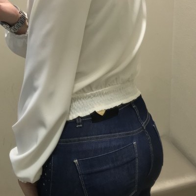 Pessoa de costas com camisa branca e calças de ganga azul escuro num ambiente interior