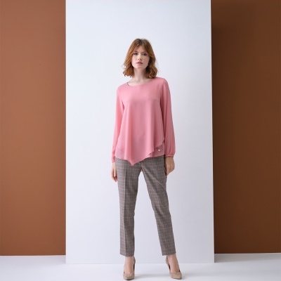 Modelo veste blusa rosa de manga comprida e calças xadrez com sapatos de salto