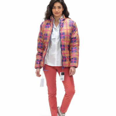 Mulher com casaco xadrez colorido, camisa branca, calças coral e sapatilhas brancas.