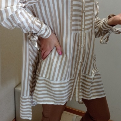 Camisa comprida riscada bege e branca com laços nas mangas, usada com leggings castanhas e sapatilhas brancas