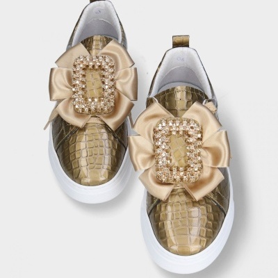 Ténis dourados com sola branca e laço com pedraria