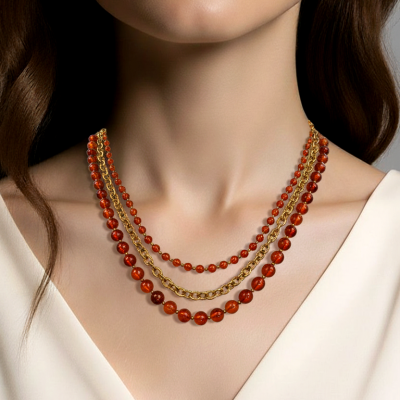 Colar triplo com contas âmbar e corrente dourada num pescoço feminino com vestido branco.