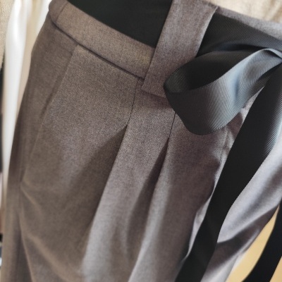 Calças cinza com cinto preto de laço e camisola bege