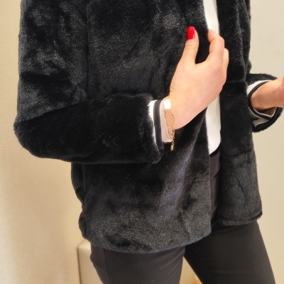 Casaco preto felpudo estilo pele usado por pessoa em ambiente interior