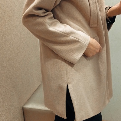 Casaco bege claro com bolso e fenda na bainha usado com calças pretas