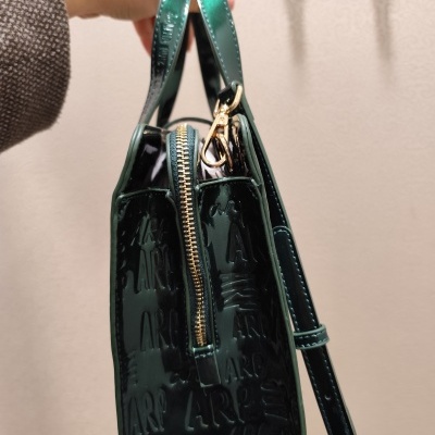 Mala de mão verde brilhante com padrão em relevo e fecho de correr dourado.