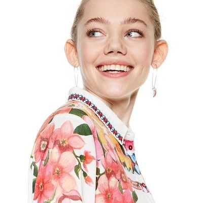 Mulher a usar camisa branca com flores rosas e gola com bordado colorido