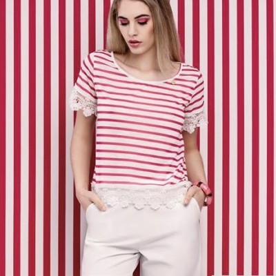 Mulher com t-shirt rosa e branca de riscas e calções brancos em fundo de riscas