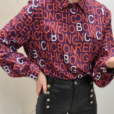 Blusa roxa com letras vermelhas e brancas e calças pretas com botões dourados