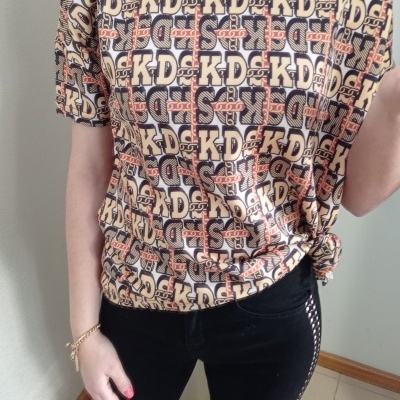 T-shirt feminina estampada com padrão KD e calças pretas justas com risca lateral prateada