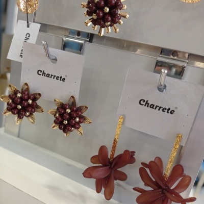 Brincos florais com detalhes vermelhos e dourados em placa transparente da Charrete
