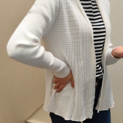 Camisola branca de malha com padrões em relevo sobre camisa de riscas e jeans azul