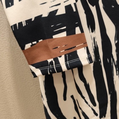 Detalhe de vestido ou camisa com padrão abstrato preto, branco e castanho