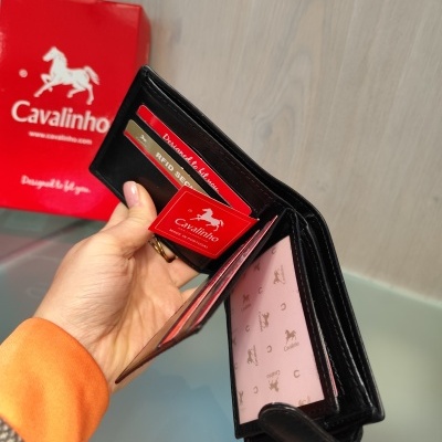 Carteira preta de pele da marca Cavalinho com interior rosa estampado e caixa vermelha da marca
