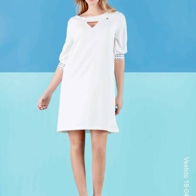 Mulher com vestido branco de mangas 3/4 e detalhe no decote em fundo azul