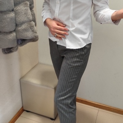 Camisa branca, calças riscas cinza, botins pretos, casaco cinza peludo pendurado