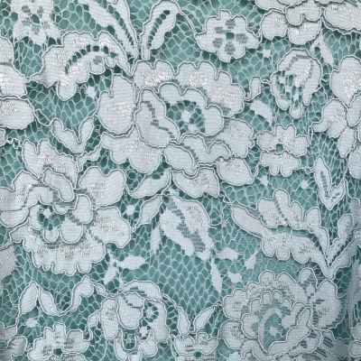 Renda branca floral sobre fundo verde com textura delicada