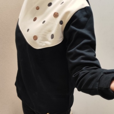 Sweatshirt preta com parte superior creme e círculos brilhantes, gola com tecido preto e branco