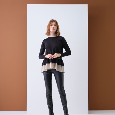 Mulher a usar camisola preta com babados bege, calças pretas tipo pele e botas pretas de salto alto