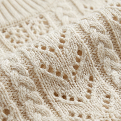Tecido de malha creme com padrão trançado e pontos vazados