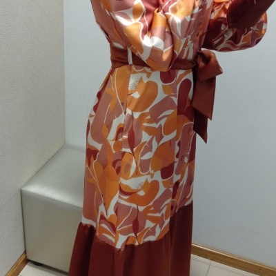 Vestido comprido com padrão abstrato em tons de laranja e castanho em ambiente interior