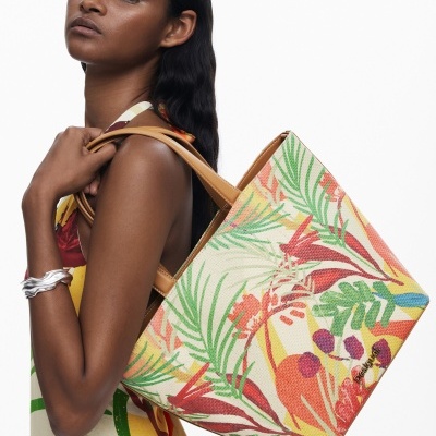 Mulher com vestido colorido e saco de mão com padrão tropical.