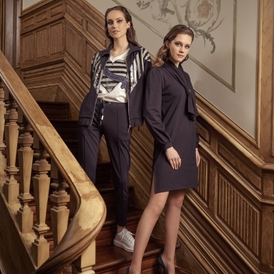 Duas mulheres vestidas formal em escada de madeira com decoração clássica