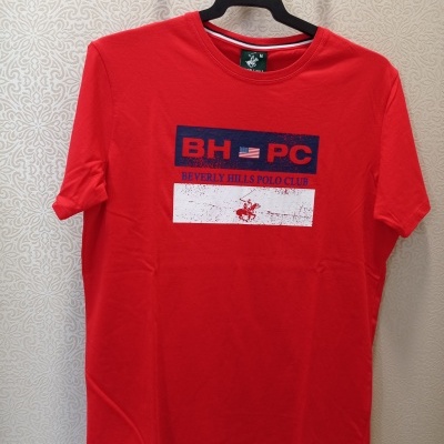 T-shirt vermelha com estampa azul e branca da Beverly Hills Polo Club pendurada num cabide.