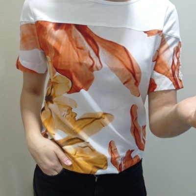 Camisola feminina branca com padrão floral em laranja e amarelo e mangas curtas