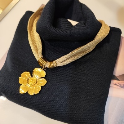 Suéter preto de malha com colar dourado com pendente em flor