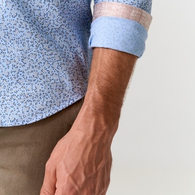 Camiseta azul clara de manga comprida com padrão floral e detalhe na manga dobrada