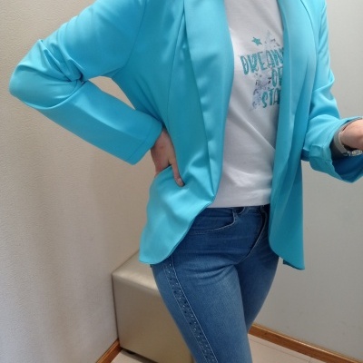 Blazer azul claro de mulher com t-shirt branca estampada e jeans azuis