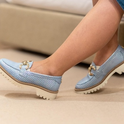 Sapatos mocassim azuis com solas brancas e detalhe dourado