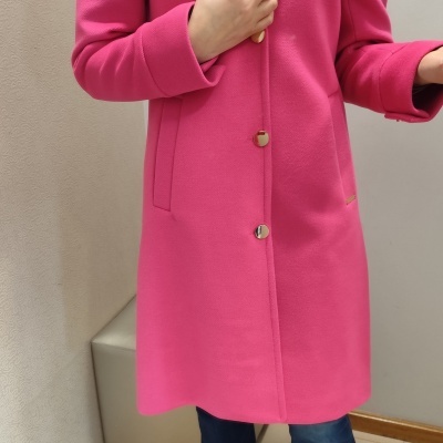 Casaco rosa com botões dourados e gola larga, usado com camisa branca e calças jeans.