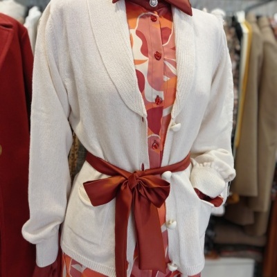 Cardigã branco com cinto castanho sobre vestido floral laranja e vermelho