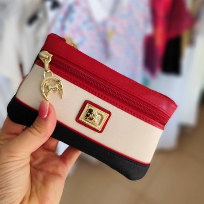 Carteira pequena em tecido vermelho, bege e preto com fecho e pendente dourado.