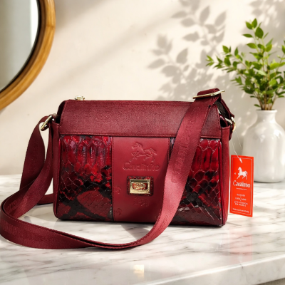 Mala de senhora bordô com textura de pele de réptil e couro, alça em tecido e etiqueta vermelha Catalimo.