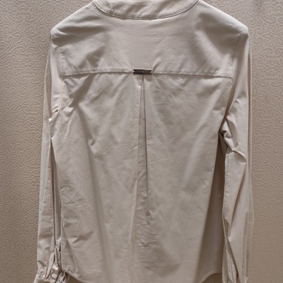 Camisa bege clara de manga comprida pendurada num cabide preto