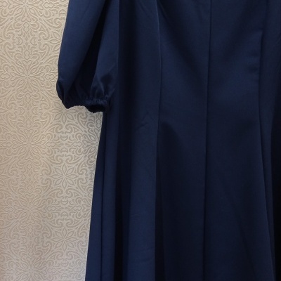 Vestido azul escuro com mangas bufantes em cabide contra parede clara