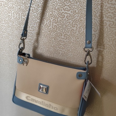 Mala bege e azul com tira azul pendurada em parede com padrão ornamental