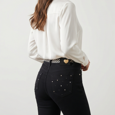 Calças pretas com aplicações metálicas e cinto listrado com fivela dourada em forma de coração