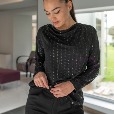 Blusa preta com lantejoulas e calças pretas em ambiente interior