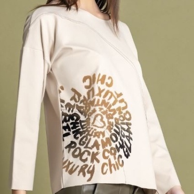 Camisola bege com padrão gráfico e calças verde-oliva numa modelo em fundo neutro