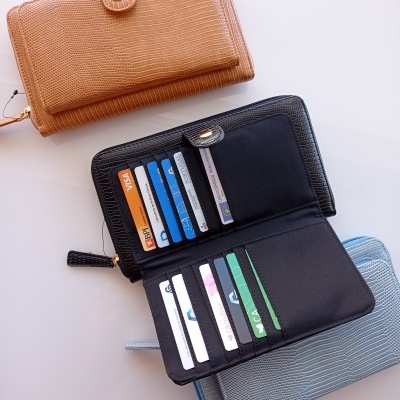 Carteiras em castanho, preto e azul com textura imitação pele de réptil, preta aberta mostrando cartões