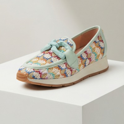 Sapato tipo mocassim com padrão colorido em tecido bordado e detalhes verdes.