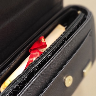 Mala preta aberta com livro dentro e fita vermelha