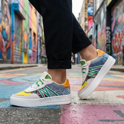 Ténis multicoloridos com padrão abstrato e sola branca usados com calças pretas em rua grafitada